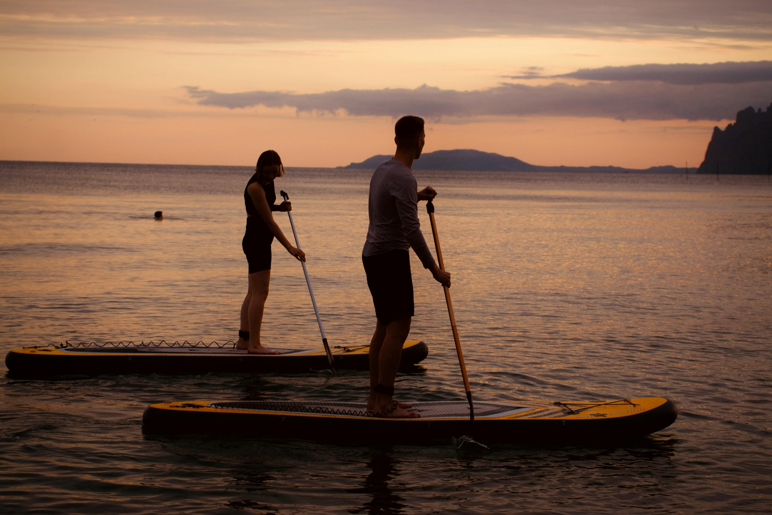 couple paddleboarding during sunset